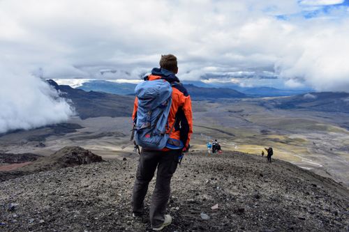 Free Traveler enjoying a breathtaking view on a mountain trek in Cotopaxi, Ecuador, amidst clouds and rugged terrain. Stock Photo