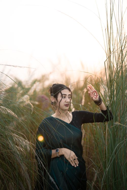 Free A woman in traditional attire standing amidst Kansas grass under soft sunlight in Bangladesh. Stock Photo
