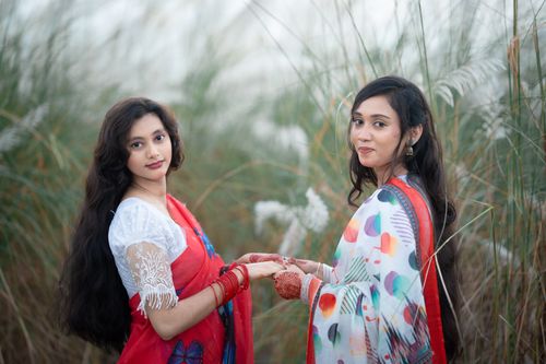 Free Elegant portrait of two Bengali women among Kash flowers in rural Bangladesh, showcasing traditional attire. Stock Photo