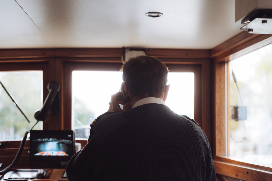 Rear view of a boat captain using radio communication inside a ship's cabin in Amsterdam.