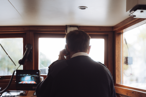 Free Rear view of a boat captain using radio communication inside a ship's cabin in Amsterdam. Stock Photo