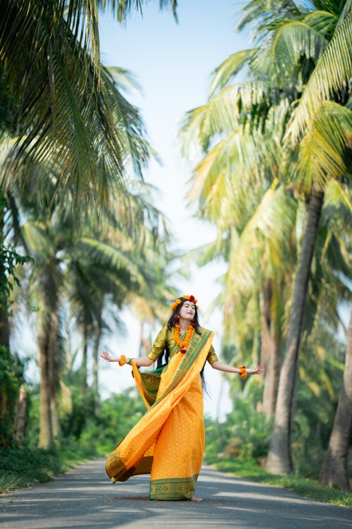 Free Beautiful South Asian woman in a yellow saree amidst scenic palm tree landscape in Bangladesh. Stock Photo