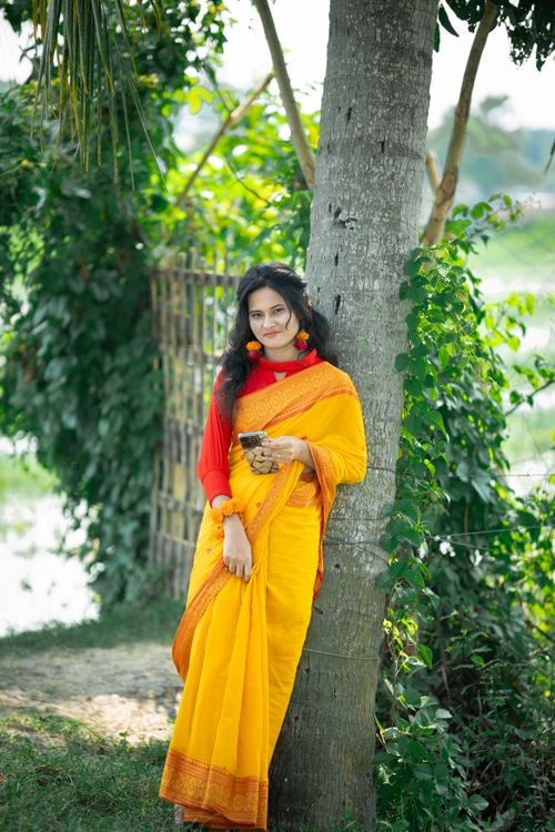 Free Portrait of a woman in a traditional yellow saree outdoors in Bangladesh. Stock Photo