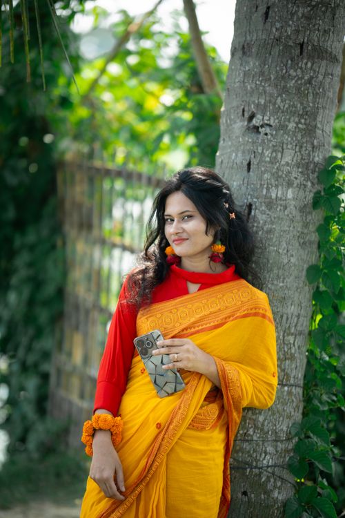 Free Beautiful woman in traditional yellow saree enjoying outdoors in Bangladesh. Stock Photo