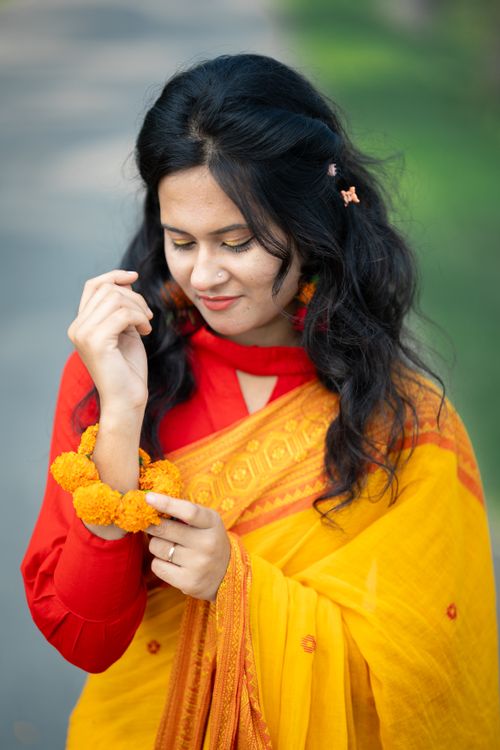 Free Portrait of a woman in a yellow saree enjoying a day outdoors in Bangladesh. Stock Photo