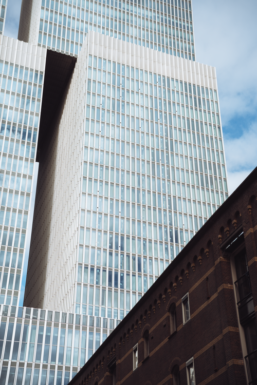 Free Tall modern skyscraper against blue sky in Rotterdam, showcasing urban architecture. Stock Photo