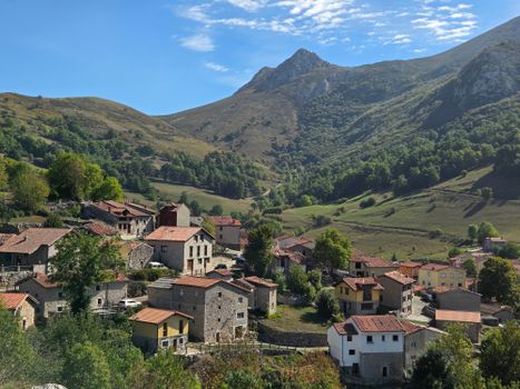 A picturesque view of Sotres village surrounded by mountainous landscape under a clear blue sky.
