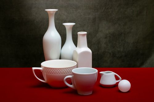 Free Minimalistic arrangement of white porcelain vases and cups on a red surface, showcasing elegance and simplicity. Stock Photo