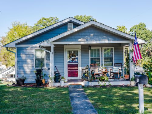 Free Charming blue house with porch seats and American flag in a suburban neighborhood. Stock Photo
