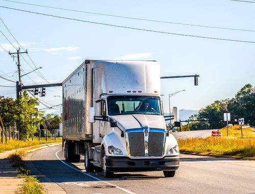 Free White semi-truck driving on a sunny rural road at daytime. Clear sky and natural surroundings. Stock Photo