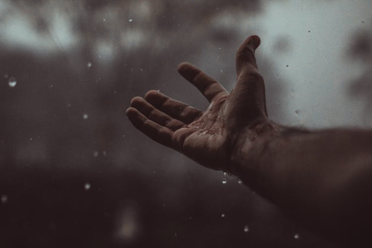 Raindrops Falling On A Person's Hand