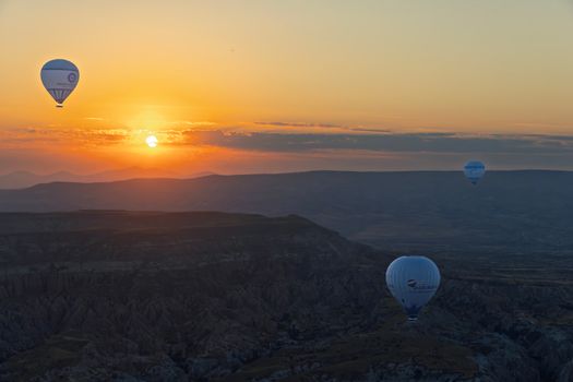 Scenic view of hot air balloons floating over Cappadocia's unique landscape at dawn.