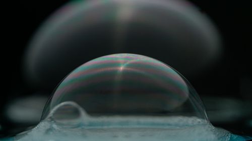 Free Close-up of a soap bubble showcasing stunning iridescent patterns against a dark background. Stock Photo