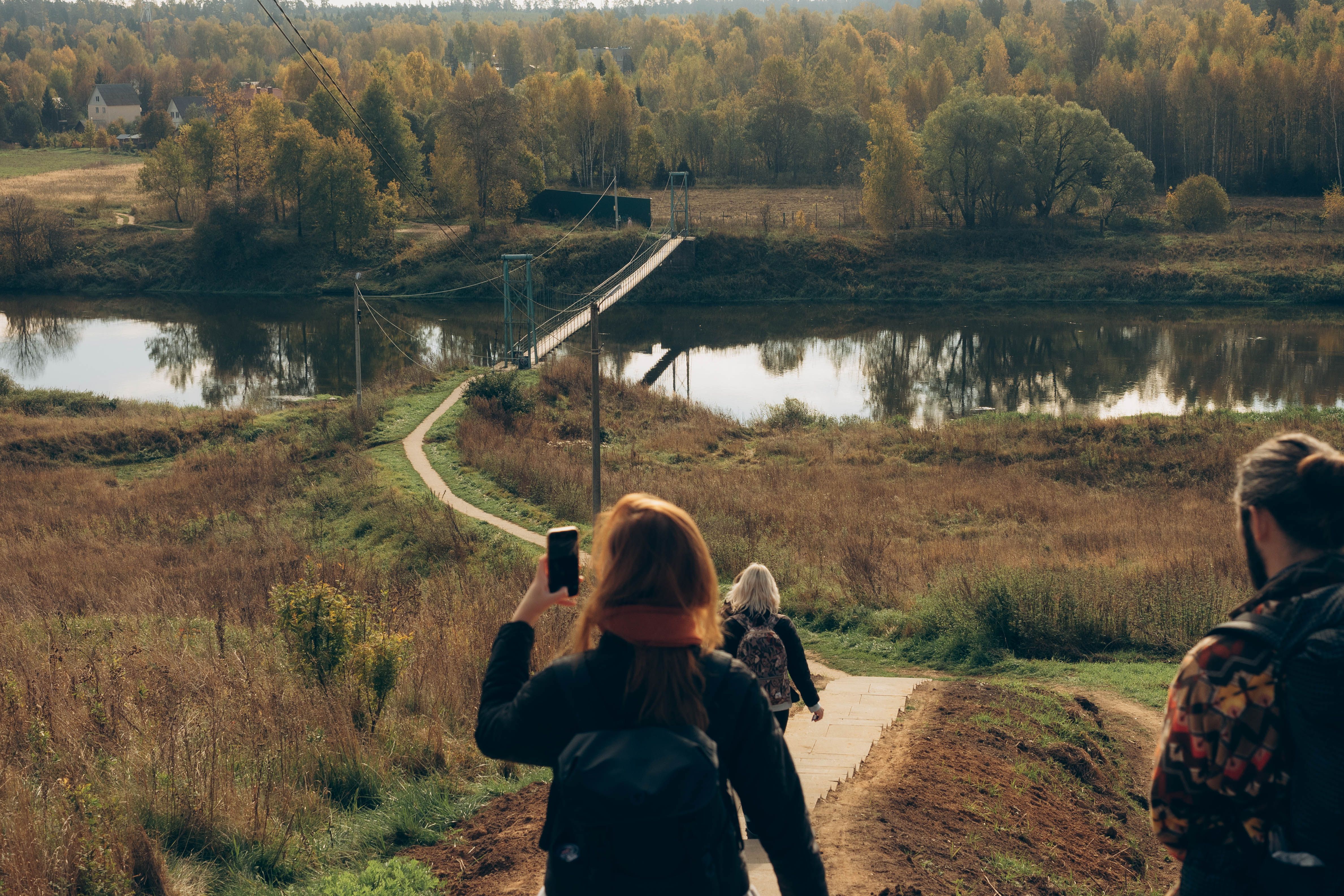 Hikers Crossing Scenic Wooden Bridge in Autumn · Free Stock Photo