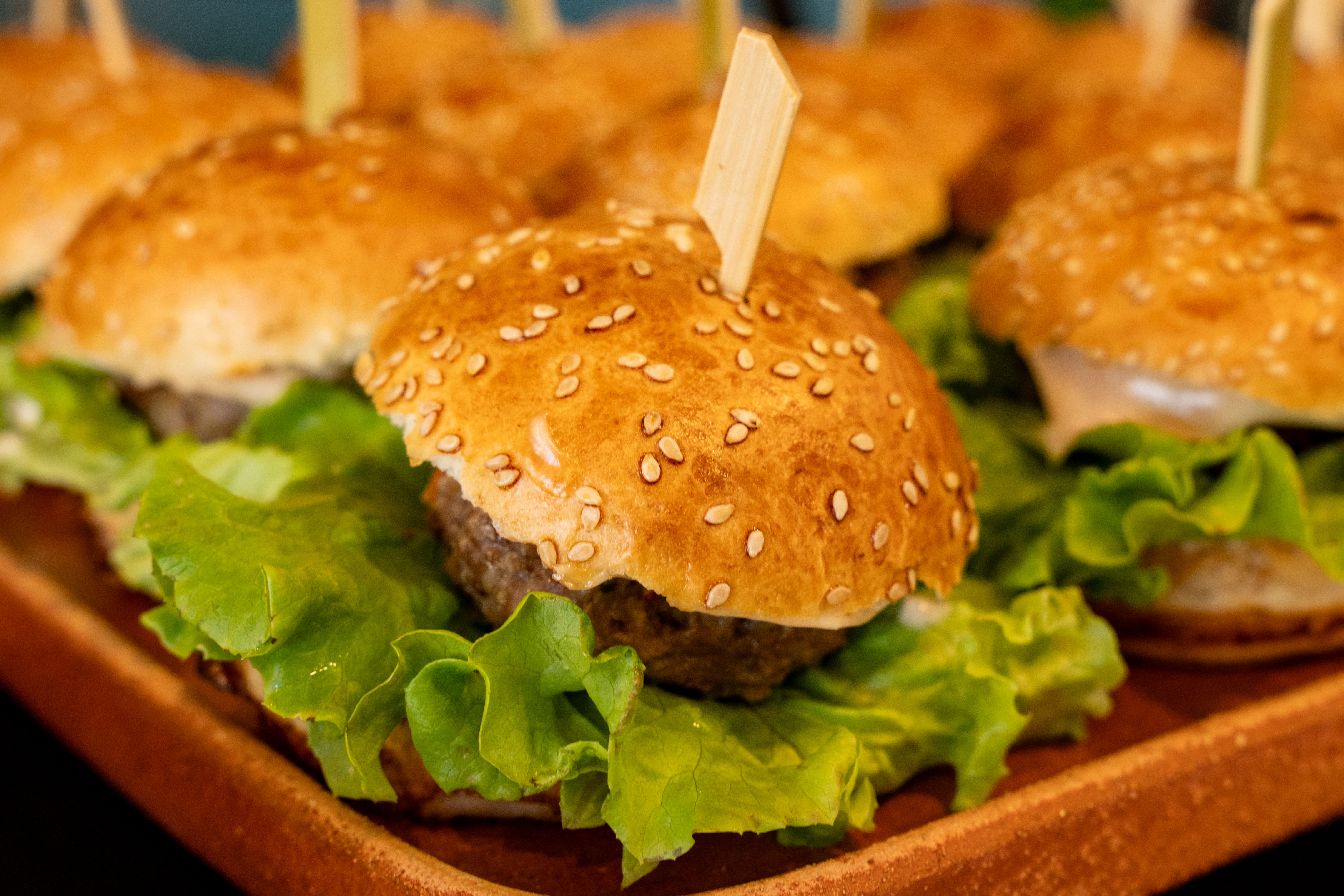 Delicious mini hamburgers with lettuce on a platter. Perfect for parties or casual dining.
