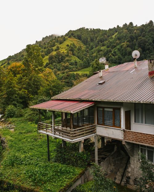 Free A picturesque mountain cabin surrounded by lush green hills and dense forest, ideal for serene getaways. Stock Photo