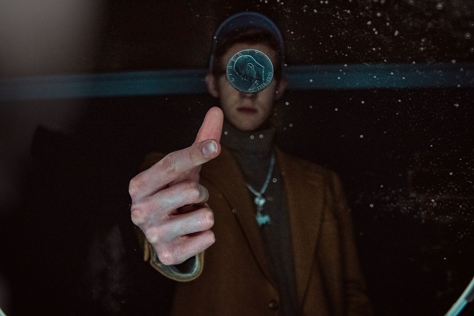 A person flips a coin into the air in a dark room