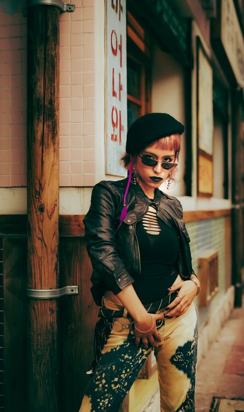 Free Stylish woman in trendy attire poses in a vibrant urban street setting, embodying modern fashion. Stock Photo