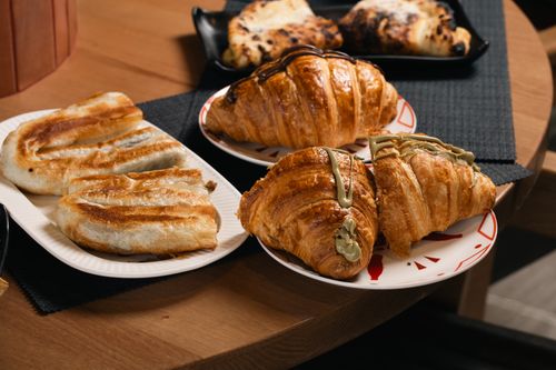 Free A variety of artisan pastries including croissants and turnovers presented on elegant plates. Stock Photo