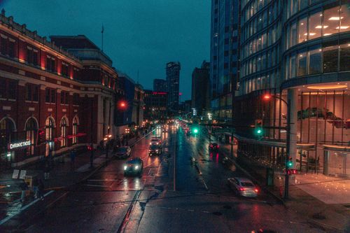Free Moody cityscape of a rainy night in downtown Vancouver, capturing illuminated streets and busy urban life. Stock Photo