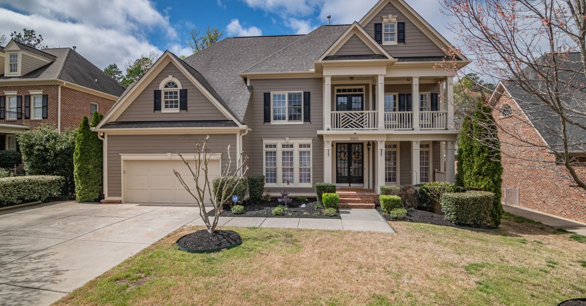 A beautiful two-story suburban house with a well-maintained lawn and elegant facade, showcasing classic architectural design.