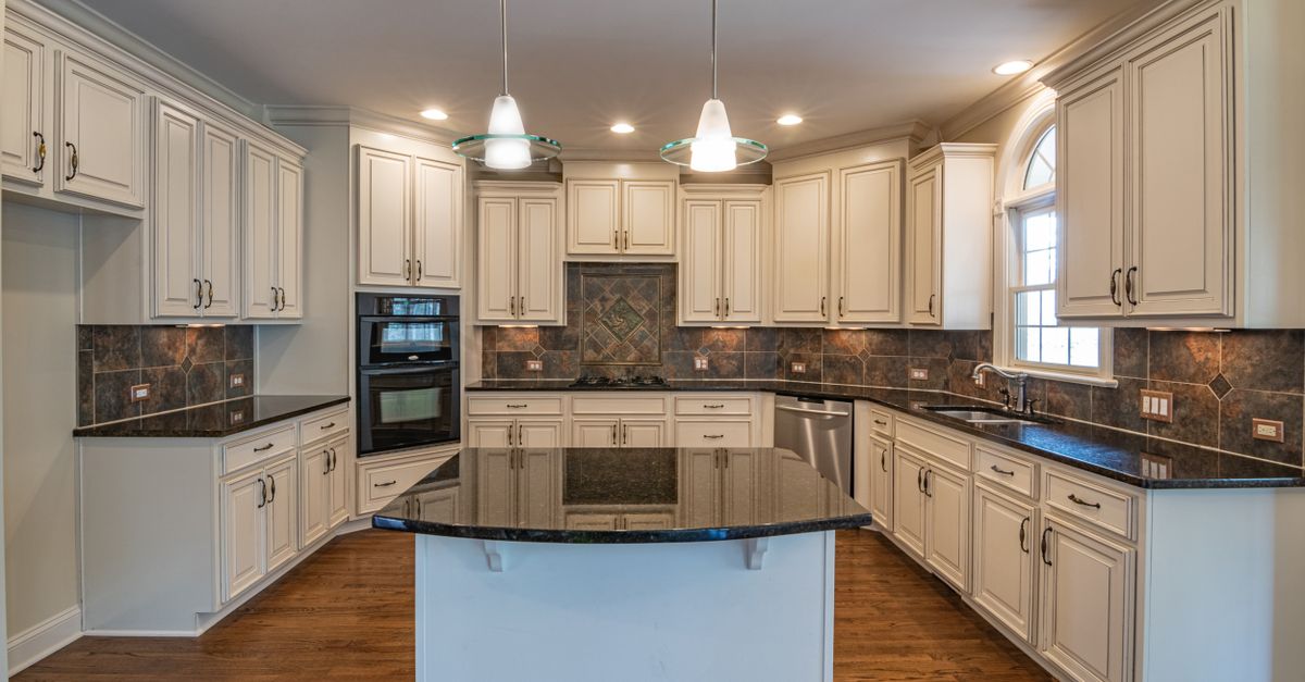 Spacious kitchen featuring elegant white cabinets, granite countertops, and modern lighting.