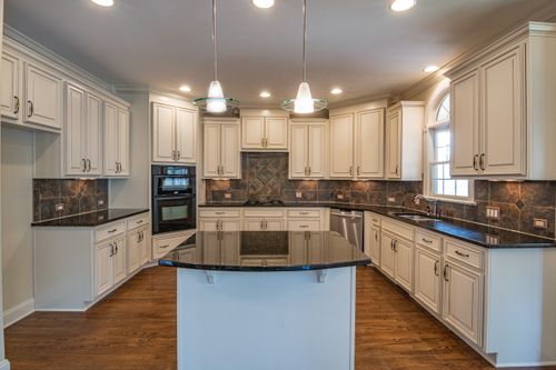 Free Spacious kitchen featuring elegant white cabinets, granite countertops, and modern lighting. Stock Photo