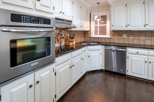 Spacious kitchen featuring white cabinets, stainless steel appliances, and wooden flooring.