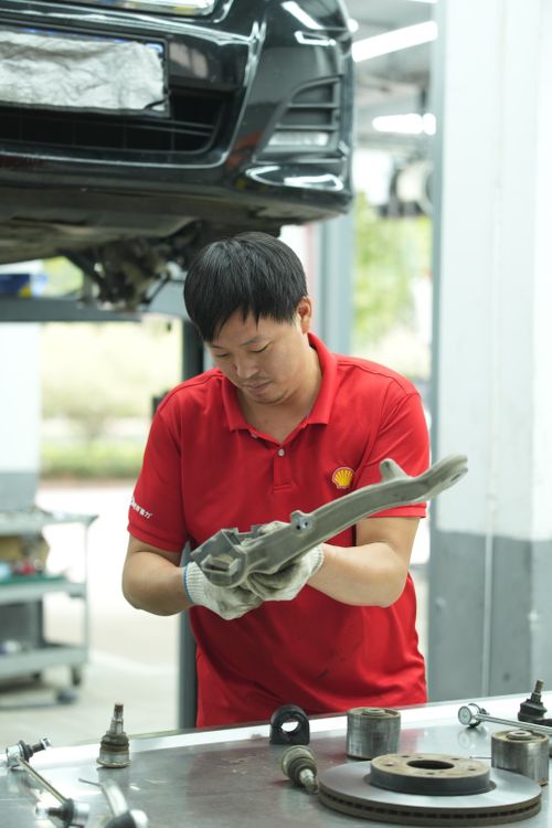 Free Mechanic in red shirt repairs car part in a professional auto garage. Stock Photo