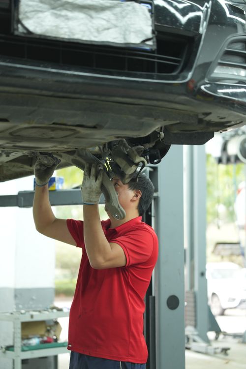 Free Mechanic works under a car in a professional automotive garage. Stock Photo