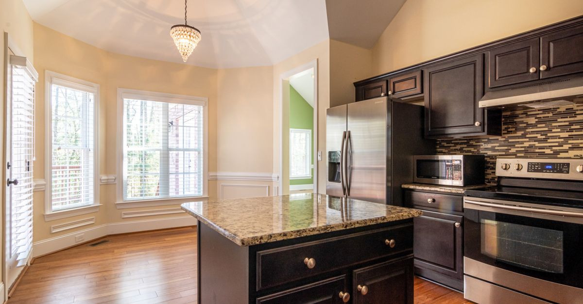 Traditional kitchen with dark brown cabinets, granite island, and wood floors.