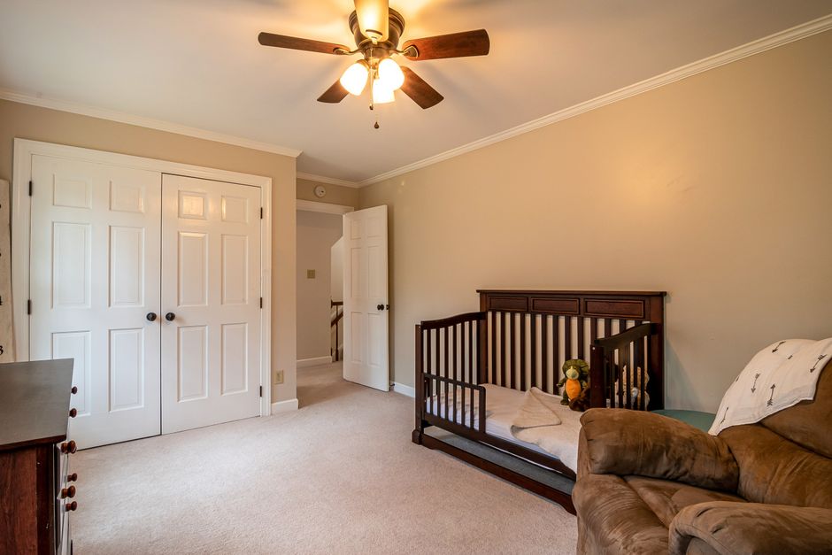 What Safety Research Reveals About Cribs, Monitors, and Sleep Gear A warm and inviting nursery featuring a crib, sofa, and ceiling fan in a spacious room.