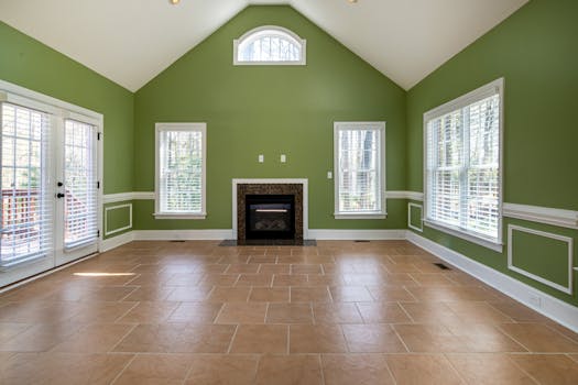 Elegant empty living room featuring green walls, a fireplace, and tiled flooring.