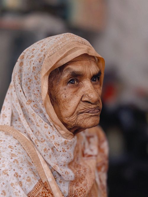 Free Close-up portrait of a senior woman wearing a traditional patterned headscarf indoors. Stock Photo