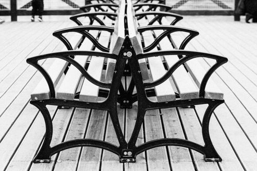Free Black and white photo of symmetrical park bench rows on a wooden deck, minimalist style. Stock Photo