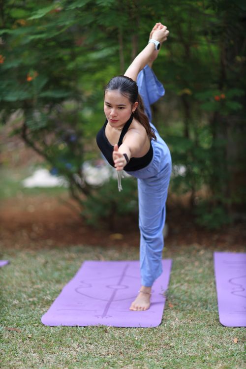 Free Young woman practicing yoga outdoors on a purple mat in Jakarta park. Stock Photo
