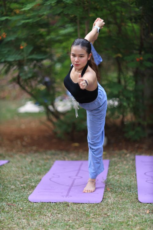 Free Woman performing yoga pose on mat in outdoor park, showcasing balance and fitness. Stock Photo