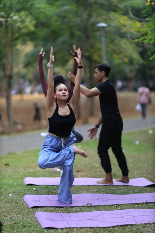 Free Group practicing yoga outdoors in Jakarta, promoting healthy lifestyle and fitness. Stock Photo
