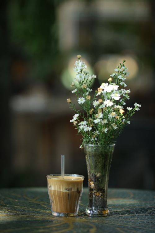 Free Aesthetic shot of iced coffee and wildflowers on a table, perfect for lifestyle themes. Stock Photo