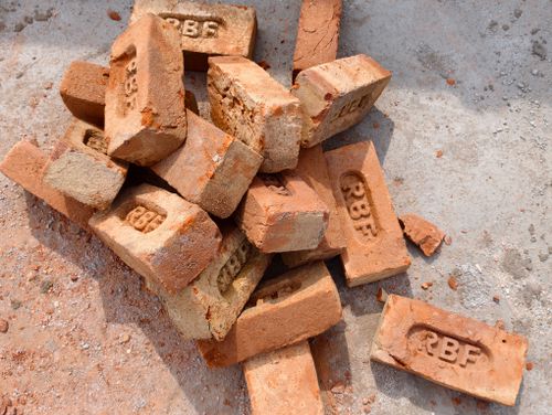 Free Close-up of a pile of rustic red bricks marked RBF at a construction site, showing natural texture and details. Stock Photo