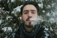 Wrinkled bearded man puffing smoke from mouth in winter