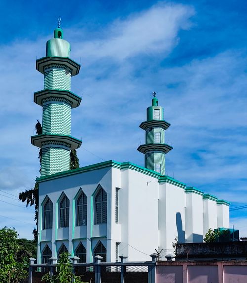 Free A striking white mosque with green minarets under a clear blue sky in Chattogram. Stock Photo