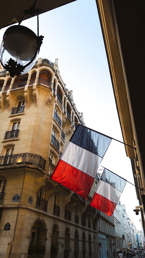 Free Elegant Paris street view with French flags and classic architecture at day. Stock Photo