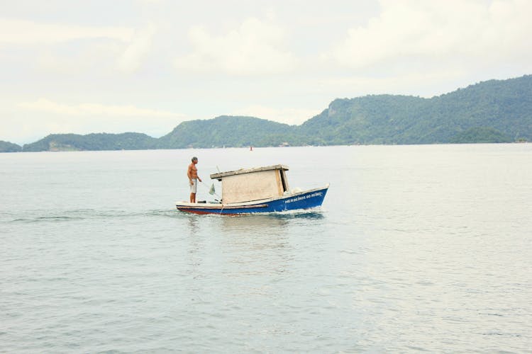 Unrecognizable Fisherman Catching Fish On Boat With Rod On Lake