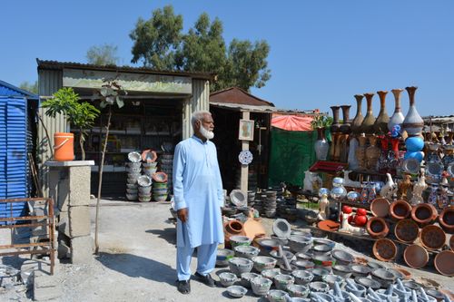 Free An artisan shop in Pakistan showcasing traditional pottery and crafts, with a shopkeeper outside. Stock Photo