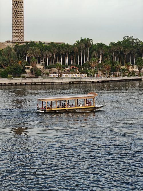 Free A scenic river cruise on the Nile with a view of lush greenery and an iconic tower. Stock Photo