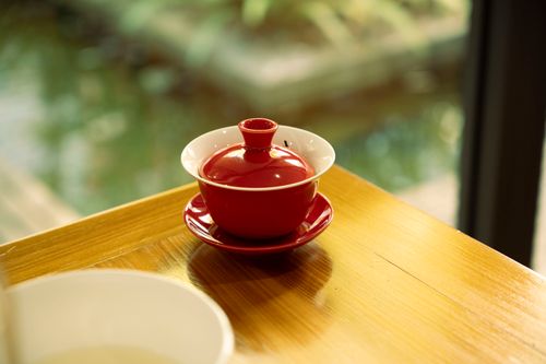 Free A vibrant red teapot sits stylishly on a wooden table, creating a warm and inviting scene. Stock Photo