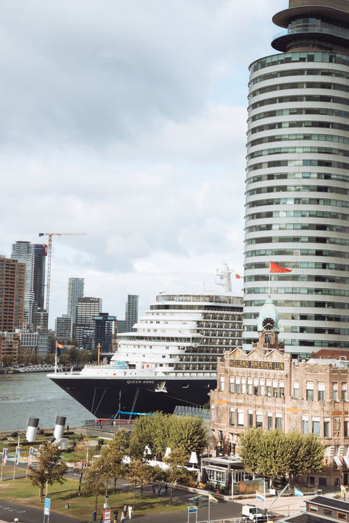 Free Cruise ship Queen Anne and Rotterdam's distinctive architecture along the Nieuwe Maas River. Stock Photo