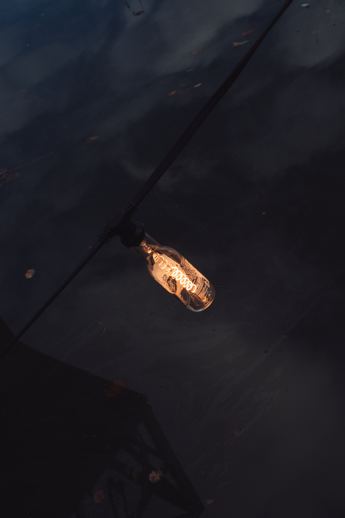Free Artistic shot of an illuminated bulb reflecting on water in Rotterdam's urban landscape. Stock Photo