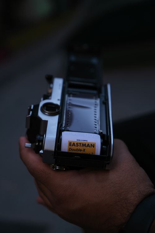 Free Person loading Eastman Double-X film into a vintage camera, close-up shot. Stock Photo